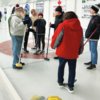 Larry Barrot (left) explains the game of curling to a group of students who came to the Heather Curling Club from Truman, Fairmont and Northrup Christian schools on March 2, 2023.